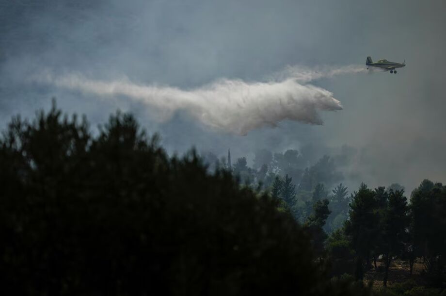 Um avião dos bombeiros israelenses usa um retardador de fogo para extinguir um incêndio depois que um foguete disparado do Líbano atingiu uma área aberta perto da cidade de Safed, norte de Israel