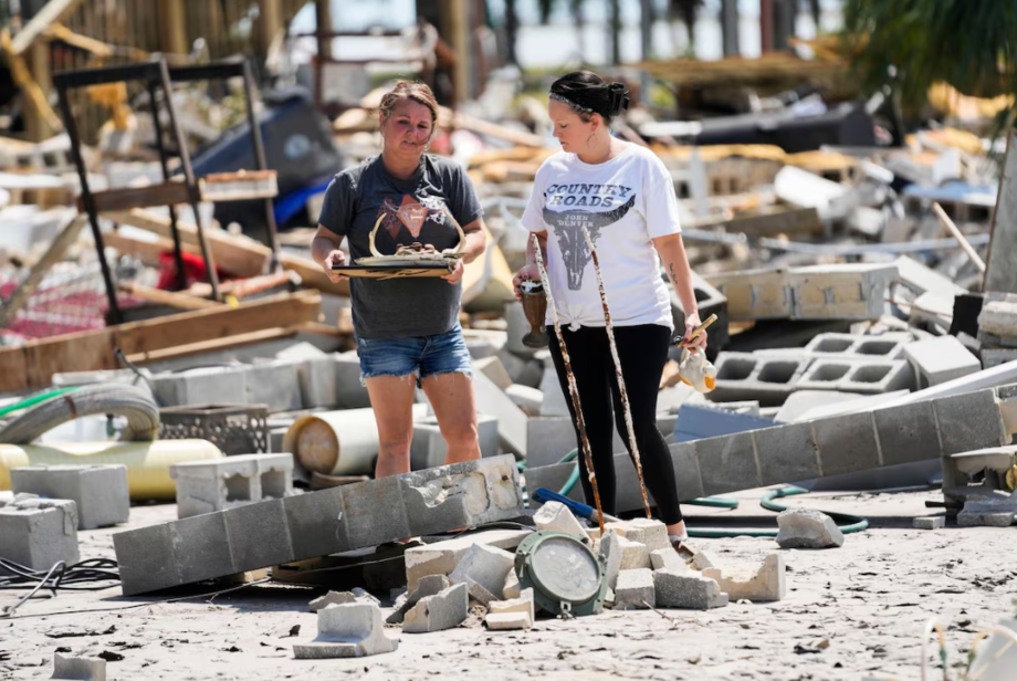 Moradoras recuperam pertences de casas destruída após o furacão Helene, em Horseshoe Beach, Flórida.