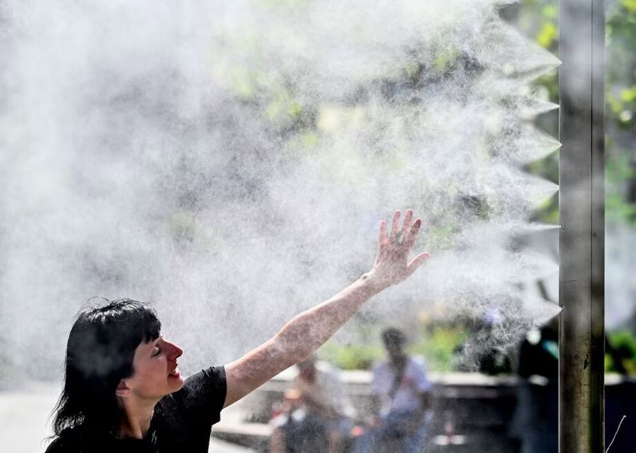 Uma mulher se refresca com um pulverizador de água em Viena, na Áustria