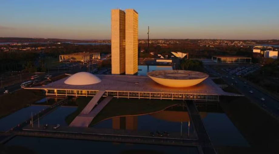 Vista aérea do prédio do Congresso Nacional com o Palácio do Planalto ao fundo.