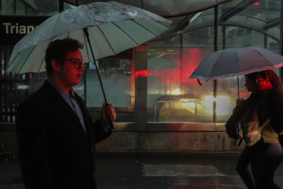 Na foto, pedestres se protegendo de chuva na cidade de São Paulo