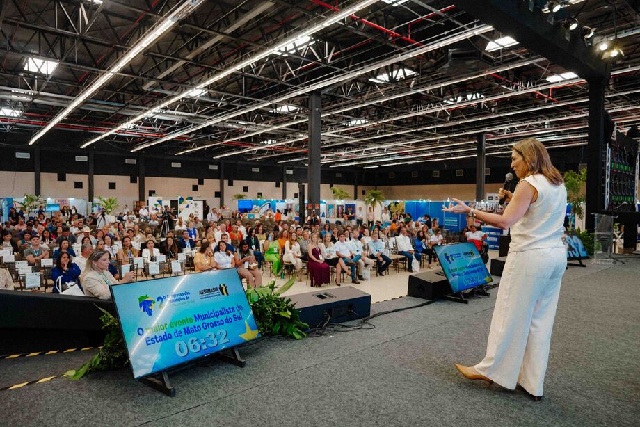 A primeira-dama de Mato Grosso do Sul, Mônica Riedel, fala para uma plateia cheia durante o 2º Congresso dos Municípios, em 6 de novembro, destacando o papel das mulheres na política e incentivando a liderança feminina. O evento é promovido pela Asso