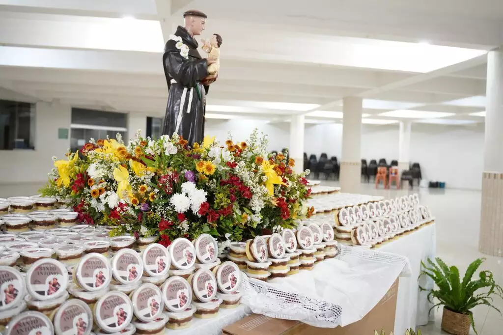 Imagem da Catedral de Campo Grande mostra a mesa com os bolos de pote de Santo Antônio, ao lado da imagem do santo casamenteiro; neste ano, 3 mil alianças foram escondidas entre os doces.