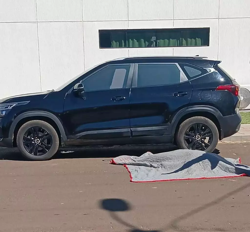 Corpo do advogado Gustavo Medina Carneiro coberto no chão, ao lado do carro SUV preto onde ele estava, em frente à escola dos filhos, no centro de Pedro Juan Caballero, na manhã desta quinta-feira (8).
