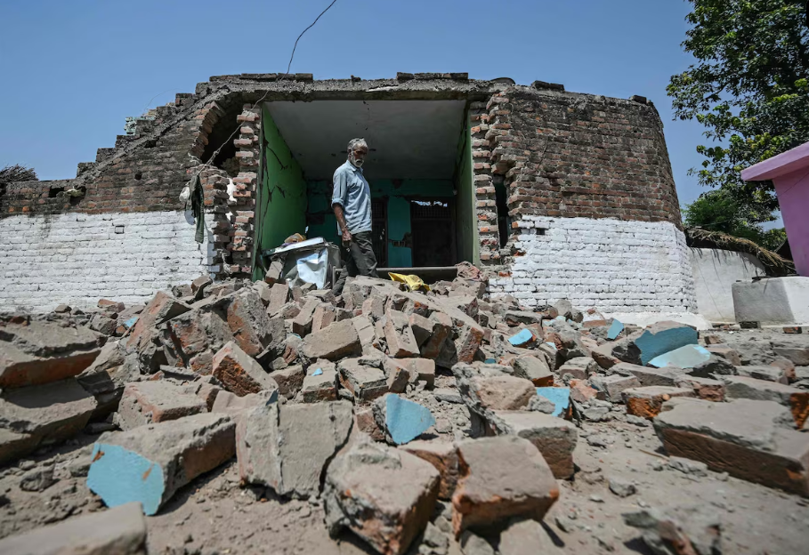 Bairi Ram está ao lado de sua casa danificada por bombardeios de artilharia paquistanesa durante a noite na vila de Kotmaira, próxima à Linha de Controle na Índia, em 11 de maio de 2025.