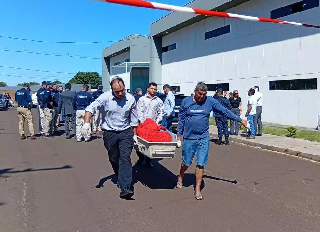 Funcionários da funerária retiram o corpo do advogado Gustavo Aníbal após execução em frente a escola, em Pedro Juan Caballero