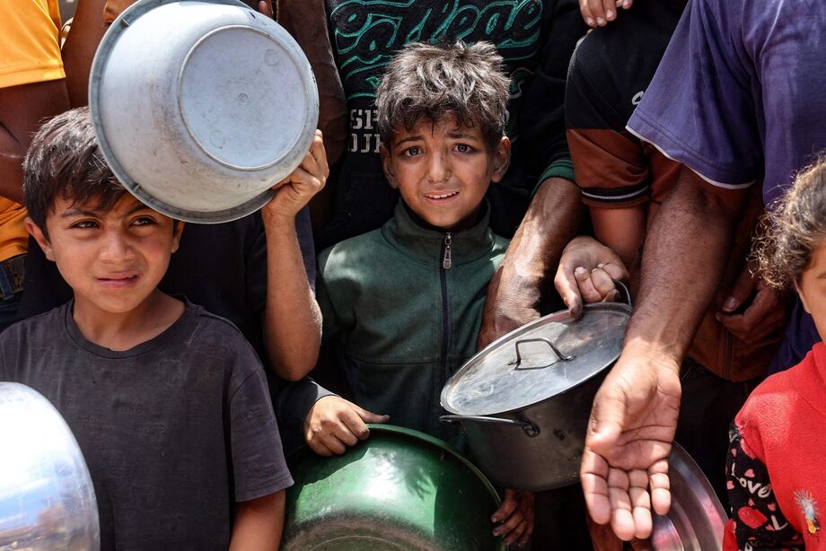 Crianças palestinas esperam na fila pela distribuição de comida em um campo para refugiados perto da Cidade de Gaza