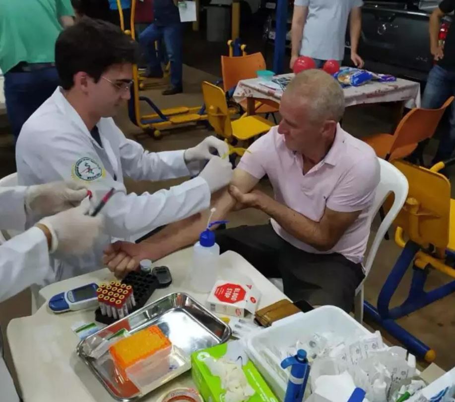 Estudante de medicina da UEMS realiza exame de sangue em caminhoneiro durante ação do projeto Saúde na Estrada, em posto de combustível em Campo Grande.