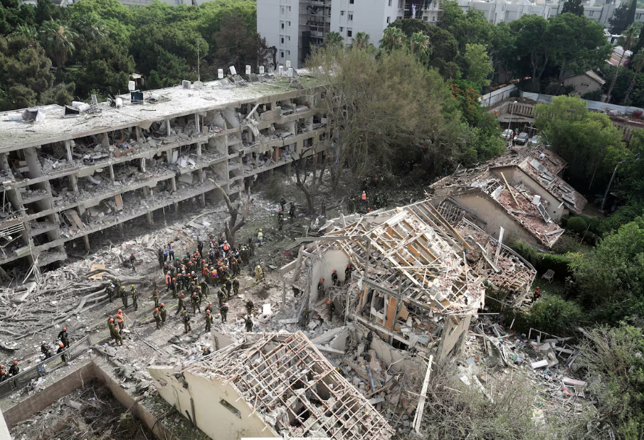 Bombeiros, equipes de resgate e militares encarregados das operações de defesa civil e recuperação se reúnem no local de um ataque direto com mísseis lançados do Irã em Tel Aviv, Israel, no domingo, 22 de junho de 2025.