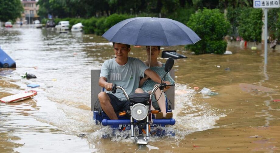 Duas pessoas atravessam rua alagada no sul da China