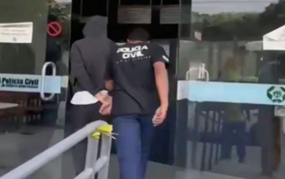 Adolescente que, segundo a polícia, confessou ter matado os pais e o irmão é conduzido por policial civil na delegacia de Itaperuna-RJ.