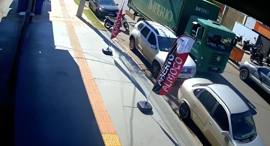 Imagem de câmera de segurança mostra o momento em que caminhão da distribuidora Império trafega ao lado de carro estacionado na Rua Bom Pastor, em Campo Grande, pouco antes da batida.