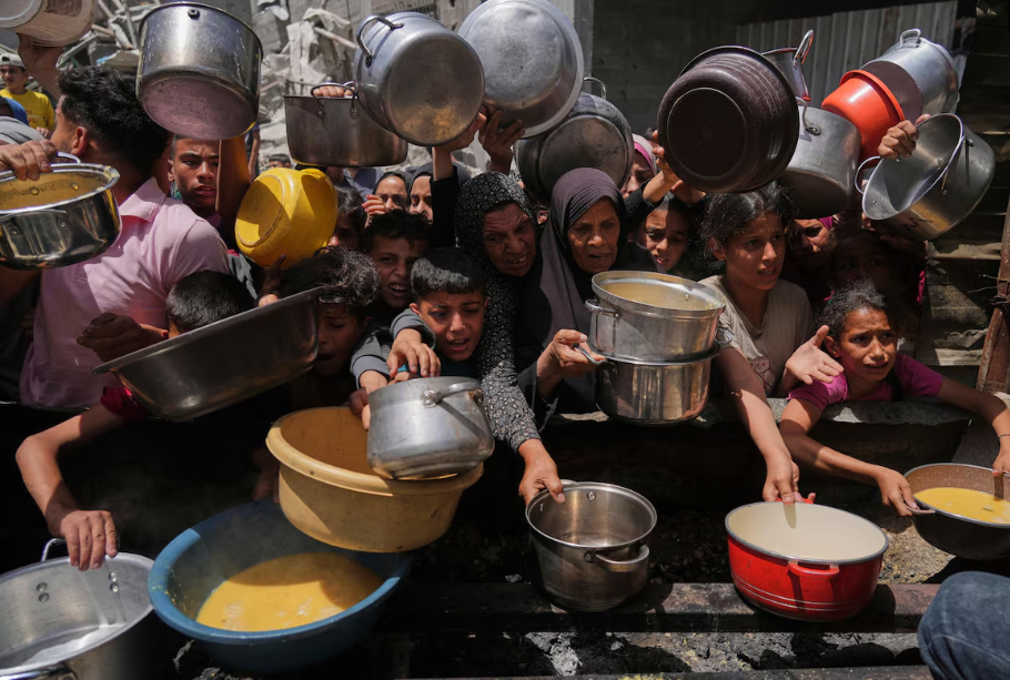 Palestinos tentam obter alimentos doados em uma cozinha comunitária em Jabalia, no norte da Faixa de Gaza