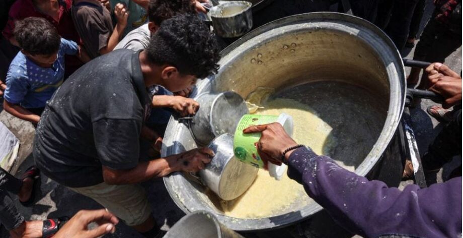 Palestinos deslocados tentam pegar o que resta em uma panela de sopa de lentilha em um ponto de distribuição de alimentos na cidade de Gaza, no norte da Faixa de Gaza, em 25 de julho de 2025.