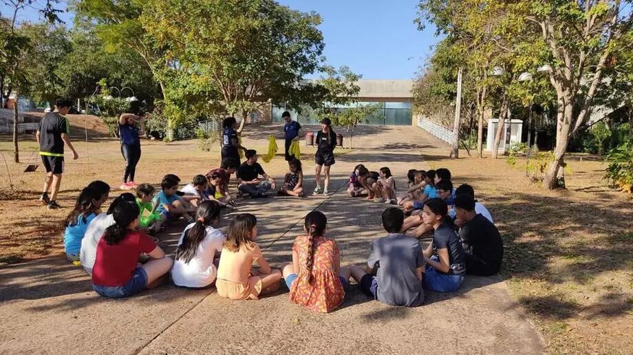 Crianças participam de atividades ao ar livre durante colônia de férias da UFMS, que oferece oficinas lúdicas para estimular o contato social e o aprendizado.