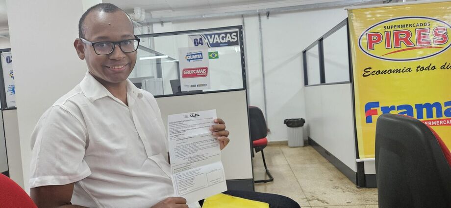 Juliano dos Santos Vicente celebra a oportunidade conquistada na Super Quarta da Funsat, segurando o documento que comprova sua participação no processo seletivo para operador de caixa.