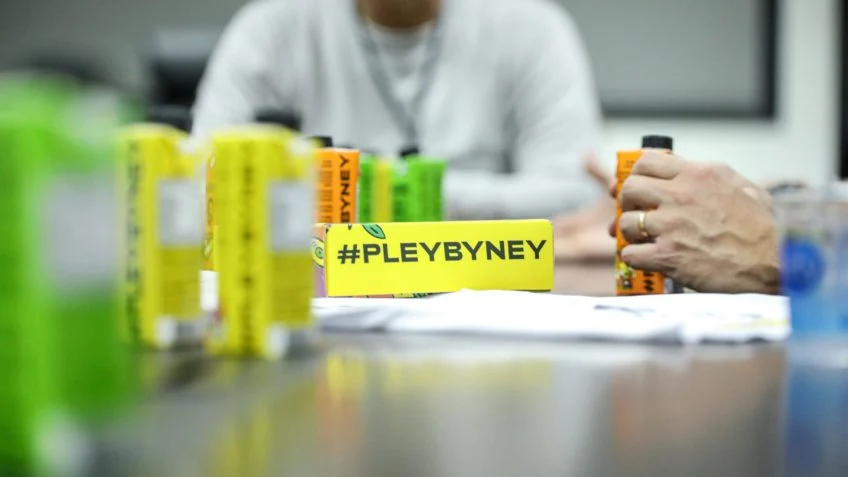 Foto mostra latas da bebida Pley by Ney, marca de Neymar Jr., alinhadas sobre a mesa durante reunião de apresentação da parceria com o Santos Futebol Clube.