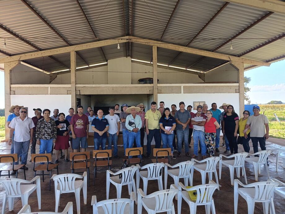 Um grupo de aproximadamente 40 pessoas posa para foto em uma estrutura coberta, semelhante a um barracão rural
