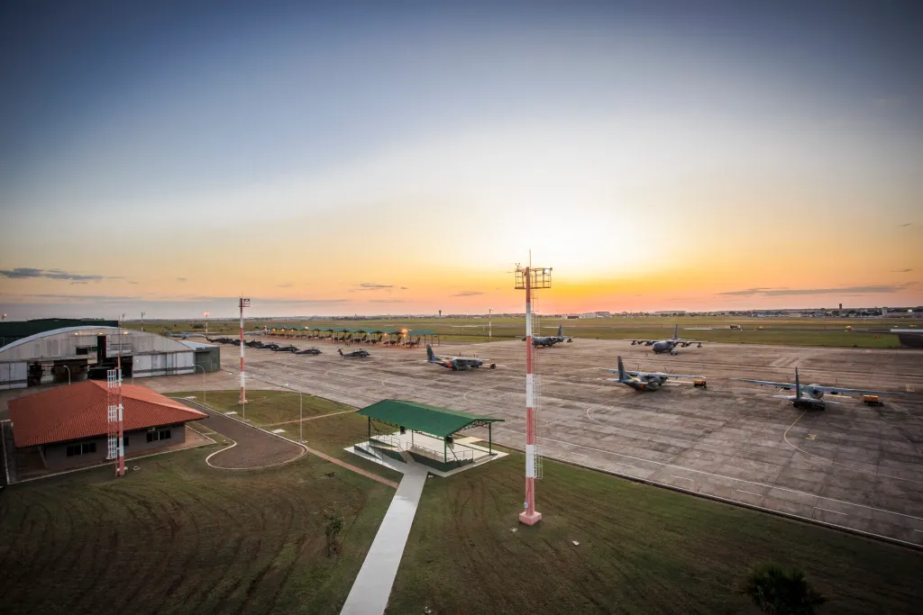 Vista panorâmica do pátio da Base Aérea de Campo Grande ao entardecer, com aeronaves militares posicionadas.