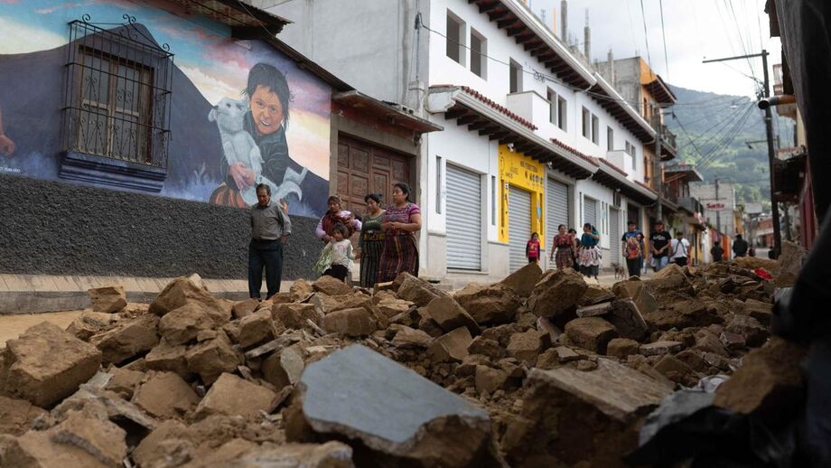 Pessoas caminham em frente ao muro de uma casa que desabou durante uma série de terremotos em Santa Maria de Jesus, Guatemala, em 9 de julho de 2025