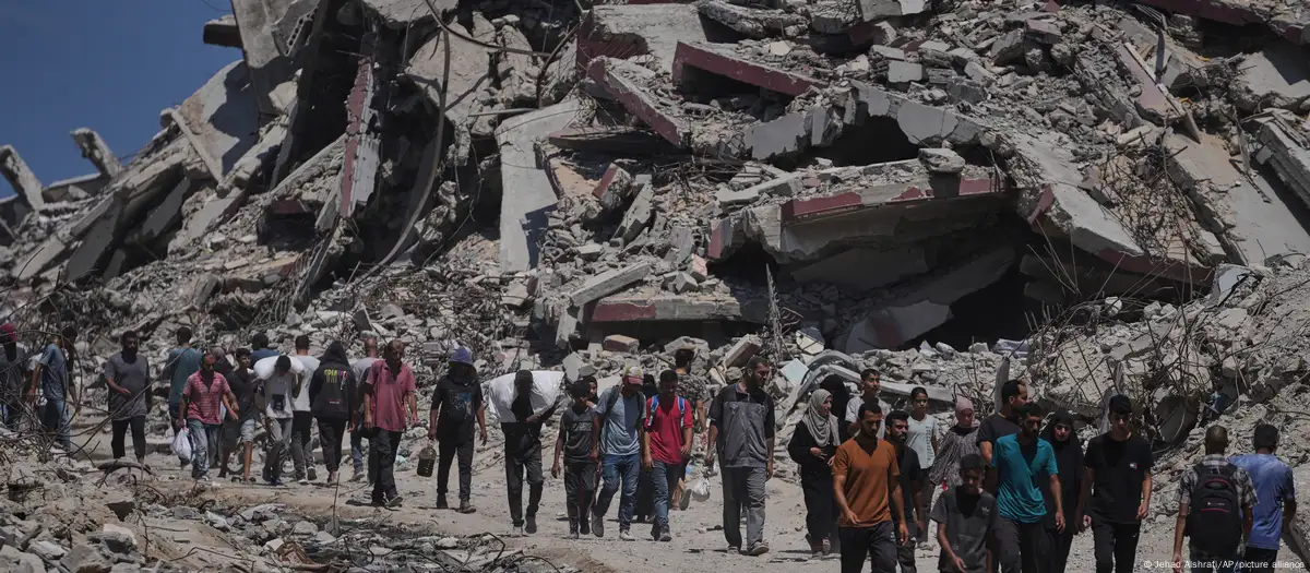 Palestinos em deslocamento carregando sacos de ajuda humanitária