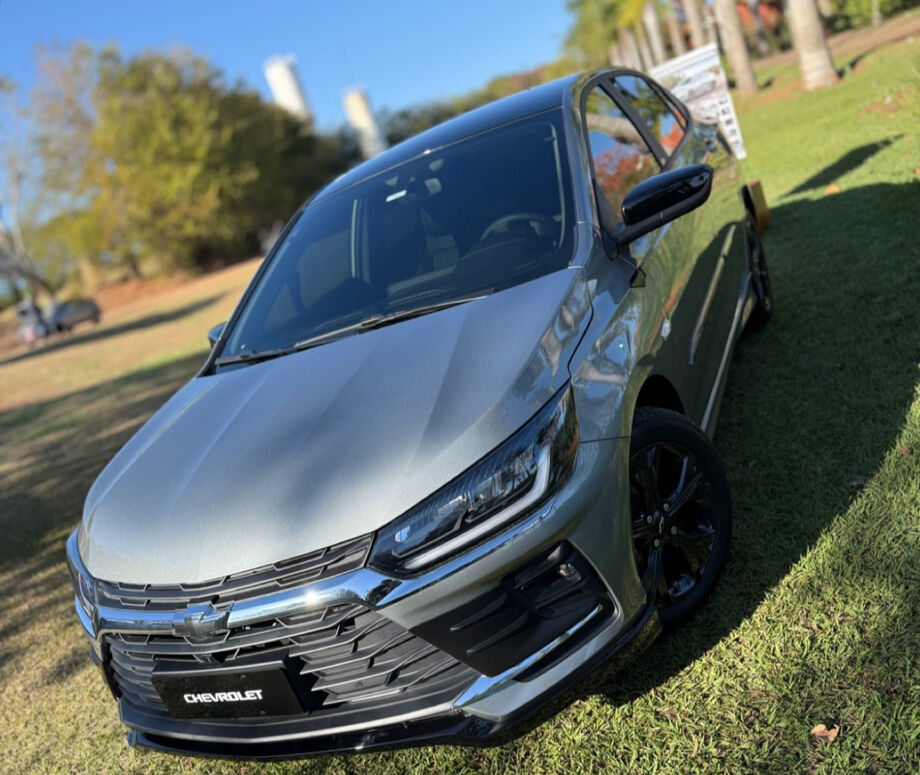 Chevrolet Onix Plus 2026 na cor prata, exibido em evento de lançamento, com novo design frontal e rodas de liga leve.