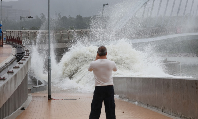 Homem observa as ondas quebrando na costa durante o tufão Ragasa, sinal 10, em Hong Kong