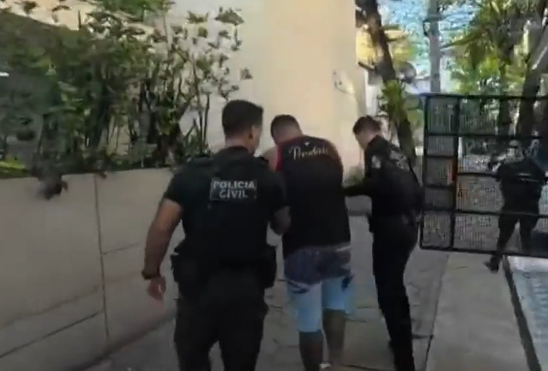 Homem é levado por agentes policiais em operação contra acusados de envolvimento na morte de torcedor do Vasco
