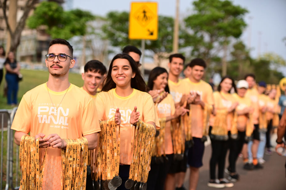 Voluntários da Corrida do Pantanal se alinham para a entrega de medalhas aos participantes ao final da prova