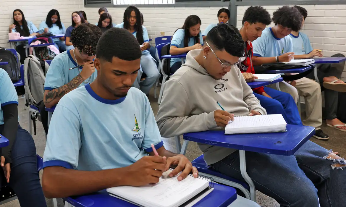 Estudantes da rede pública durante aula em escola estadual; benefício é pago conforme frequência escolar.