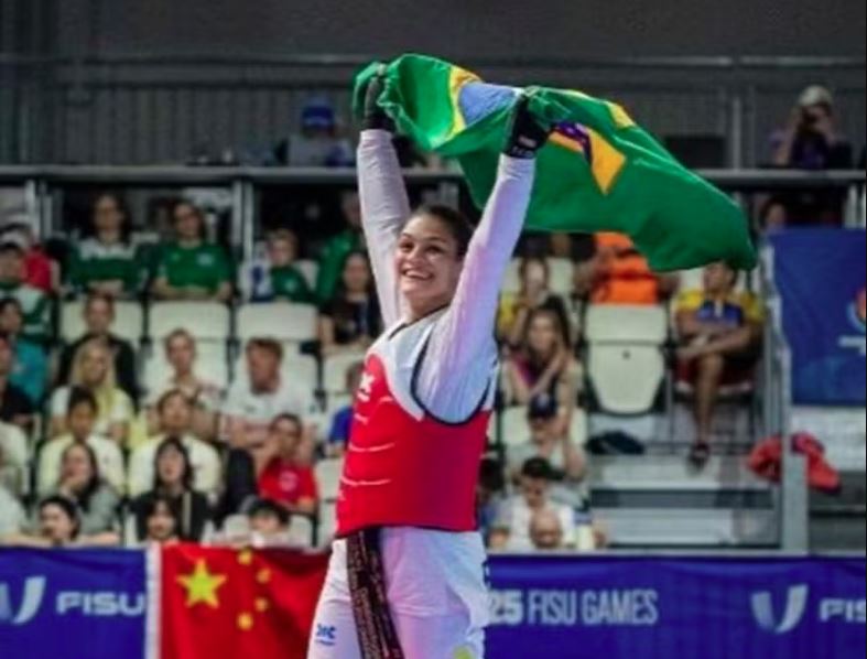 Maria Clara Pacheco ergue a bandeira do Brasil após conquistar o título mundial de taekwondo na China