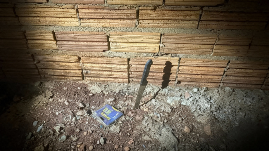 Faca encontrada ao lado da parede nos fundos do imóvel, apontada como uma das armas do crime.