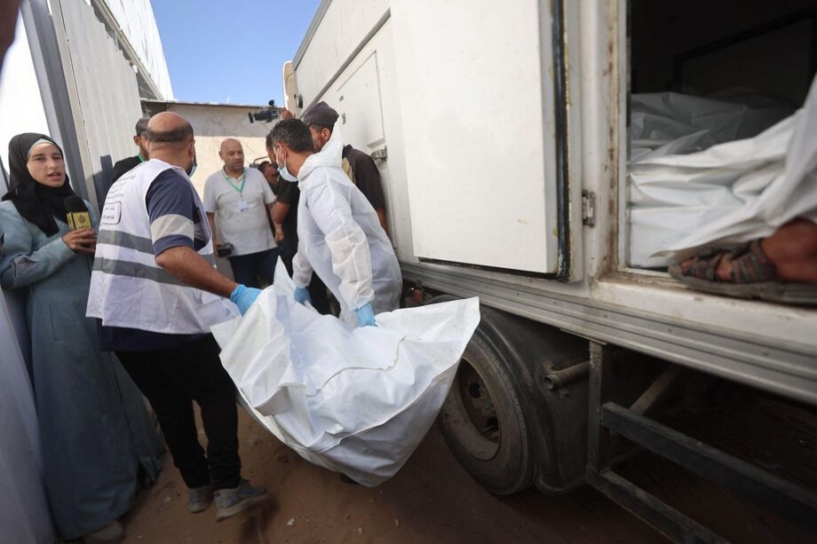 Funcionários do necrotério retiram os corpos de palestinos que estavam sob custódia israelense, após serem transportados em veículos da Cruz Vermelha.