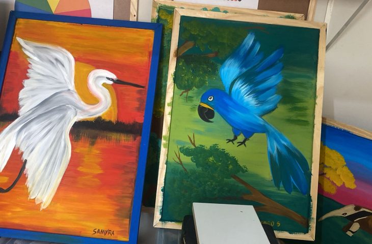 Exposição apresenta 15 obras criadas por crianças PCDs em aulas de arteterapia, com representações coloridas da fauna pantaneira.
