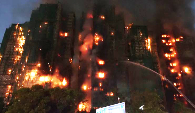 Imagem de bombeiros em ação nos escombros do prédio, com fumaça e estruturas parcialmente destruídas.