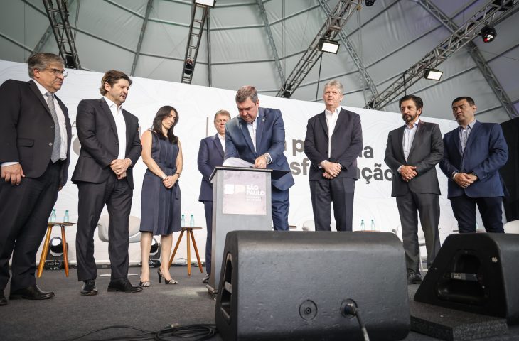 O governador Eduardo Riedel assinando o protocolo acompanhado do governador de São Paulo, Tarcísio de Freitas e o prefeito de São Paulo, Ricardo Nunes, durante o evento em São Paulo.