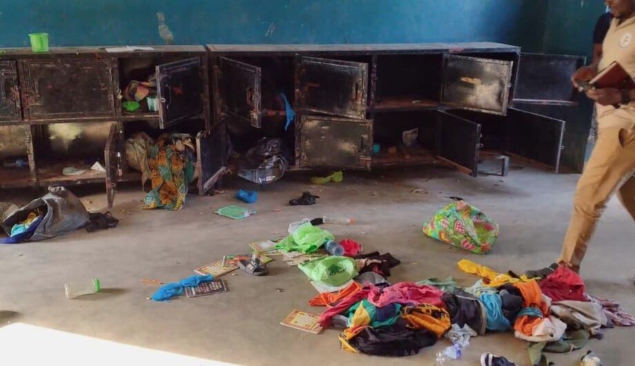 Equipes caminham ao lado de pertences na Escola Primária e Secundária Católica de Santa Maria, após homens armados sequestrarem crianças e funcionários na comunidade de Papiri, Nigéria