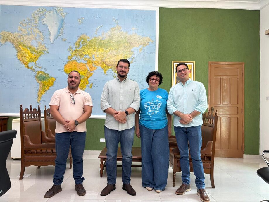 Prefeito André Guimarães ao lado dos representantes da AFS Intercultural Brasil e da equipe municipal, após reunião sobre parcerias educacionais e cidadania global.