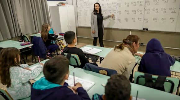 Professor aplicando atividade matemática em sala de aula com alunos do ensino fundamental