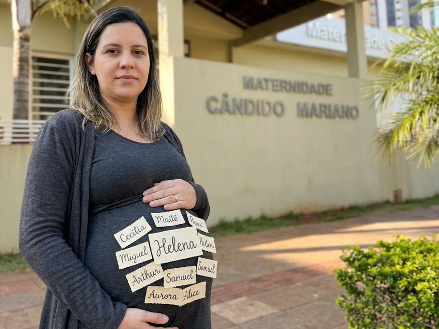 Gestante posa em frente à Maternidade Cândido Mariano com nomes que aparecem entre os mais registrados em Campo Grande em 2025, segundo dados dos cartórios.