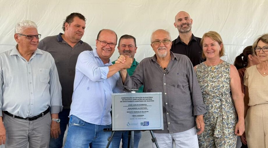 Barbosinha, ao lado do prefeito Dr. Lídio Ledesma e de autoridades locais, caminhando ou posando em rua recém-asfaltada de Iguatemi, com máquinas ou trecho de pavimentação ao fundo.