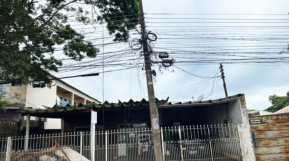 Fios de telefonia e internet pendurados em poste da Avenida General Nepomuceno Costa seguem oferecendo risco a quem passa, mesmo após lei que obriga retirada de cabos inativos.