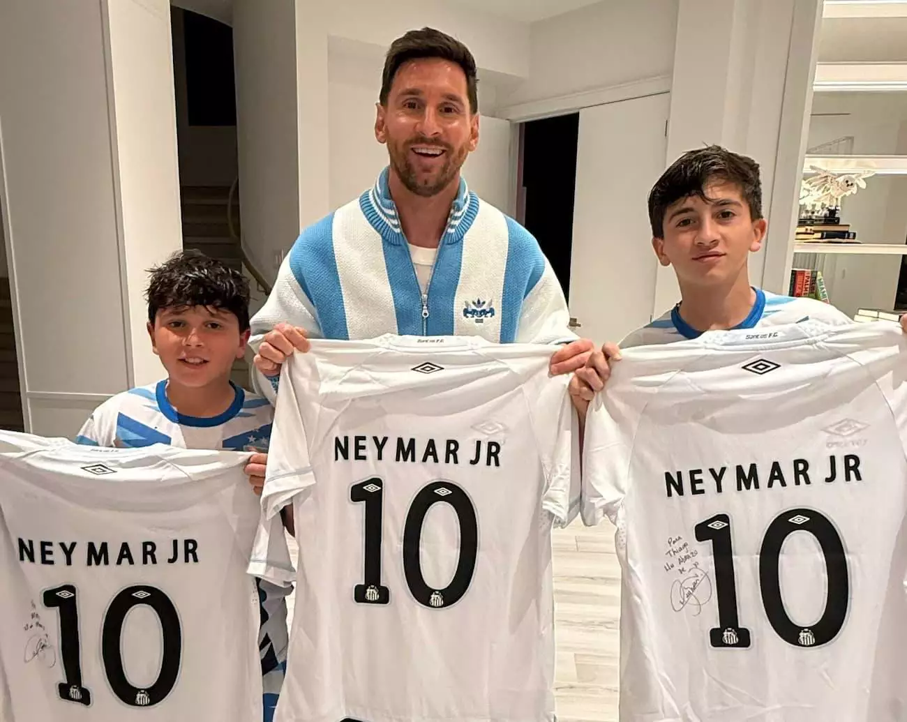 Lionel Messi e dois de seus filhos seguram a camisa do Santos autografada por Neymar, em foto compartilhada pelo clube nas redes sociais.