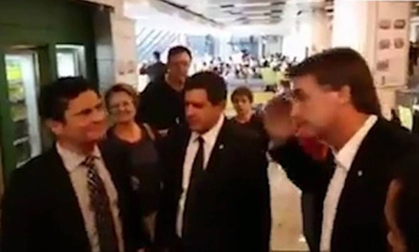 Nas imagens, Bolsonaro aparece indo em direção a Moro, que cumprimentava algumas pessoas em uma lanchonete do aeroporto. Quando chega diante do magistrado, o deputado bate continência para o juiz, que sorri e cumprimenta o parlamentar rapidamente e sem en