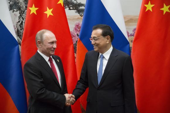 Presidente russo Vladimir Putin (E) cumprimenta o premier chinês Li Keqiang durante o fórum em Pequim