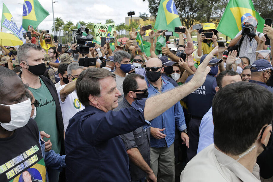 Sem máscara, o presidente da Republica, Jair Bolsonaro, cercado por um cordão de isolamento de seguranças, cumprimenta simpatizantes que participam da manifestacão de apoio ao ao governo na frente do Palácio do Planalto