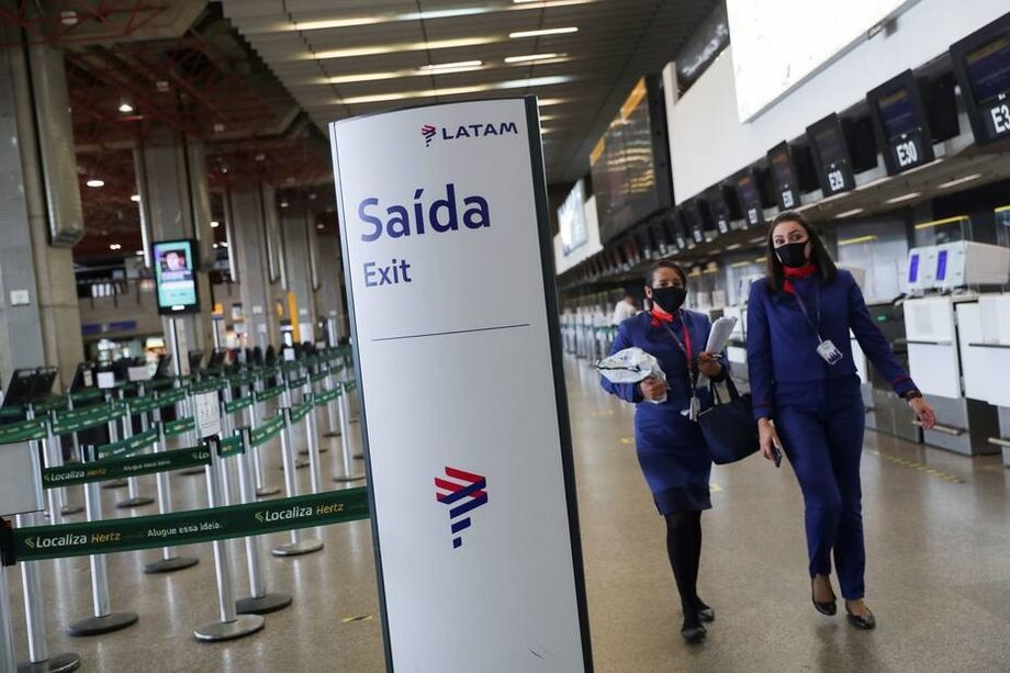 Funcionárias da Latam diante dos balcões vazios da companhia no aeroporto de Guarulhos.