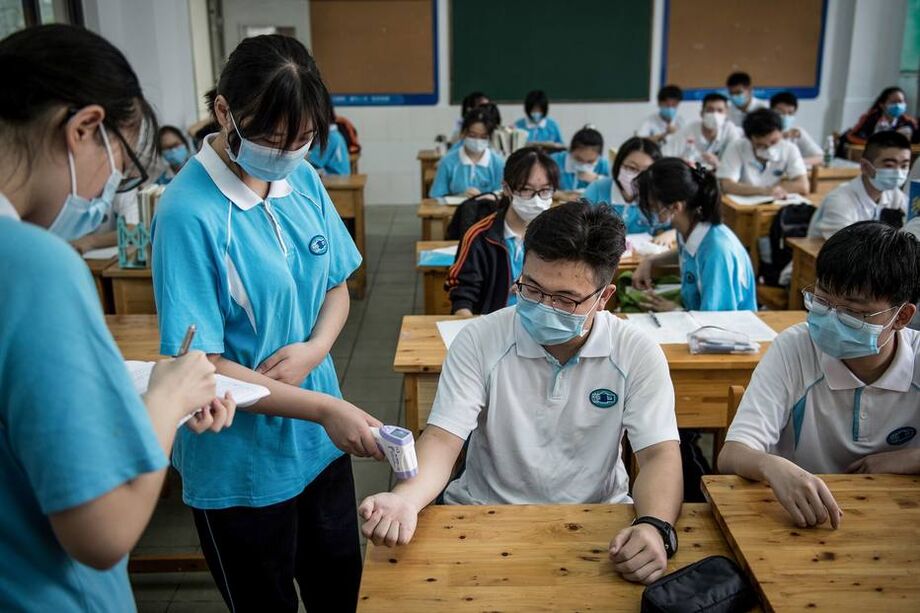 Funcionários chineses medem a temperatura de estudantes na cidade de Wuhan, na China