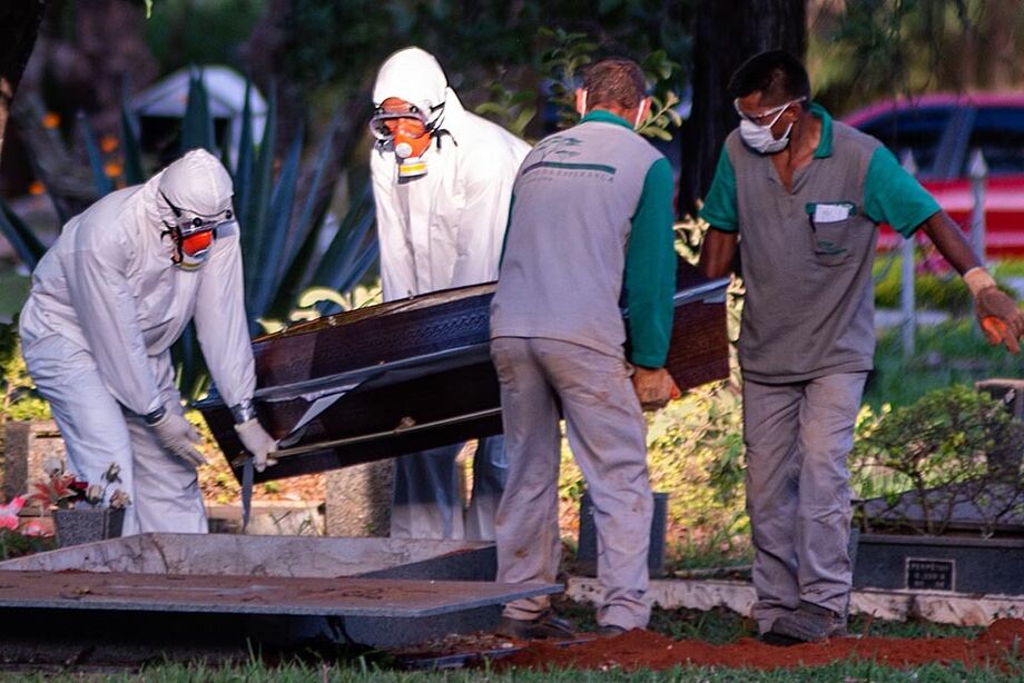Funcionários usam proteção para enterrar mortos pela Covid-19