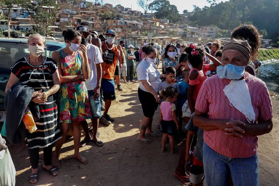 Dezenas de pessoas na fila para receber uma doação de alimentos na comunidade da Capadócia, na Brasilândia